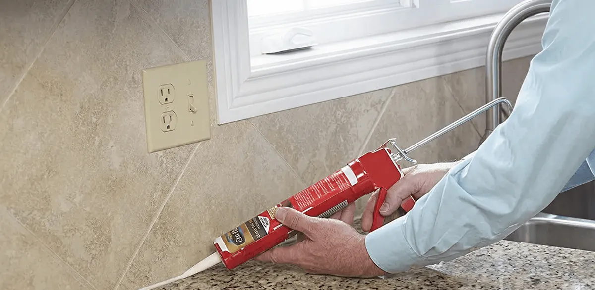 Handyman applying caulk along a kitchen backsplash and countertop seam in Stockton, CA